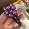 Gros plan détaillé d'une pince à cheveux fleur en cristal violet avec strass brillants. - Rose rouge
