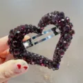 Gros plan d'une pince à cheveux en forme de cœur en strass violet foncé brillant. - Fuchsia