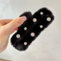Close-up detail of a black furry claw clip with sparkling rhinestones for winter hair styling. - Black