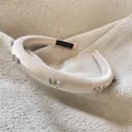 Detailopname van elegante fluwelen haarband met sprankelende kristallen vlinders en vulling. - Wit