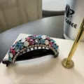 Gros plan d'une pince a cheveux courbée ornée de strass colorés sur une base noire élégante. - Opale Colorée