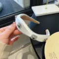 Gros plan de détail de bandeau trèfle en satin blanc avec des cristaux étincelants. - Blanc