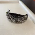 Détail rapproché d'une pince à cheveux banane en strass brillants, design en cristal élégant. - Gris