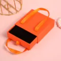 Catola portagioie a cassetto arancione con manico in nastro, ideale per anelli e bracciali. - Stile Nastro Arancione / 9*9*3.5cm (Con Spugna)