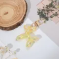 Vista detallada del llavero de perro globo iridiscente colorido con herrajes dorados para accesorios. - Amarillo Jelly