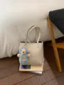Beige leather bucket tote bag with cute knit bear charm, stylish minimalist daily commuter bag. - White + Pendant