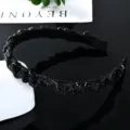 Detailed view of black rhinestone headband with ruffled texture and glittering crystal stones. - Black