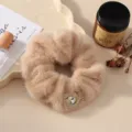 Close-up detail of fluffy plush hair scrunchie with sparkling rhinestone ornament in warm tone. - Khaki