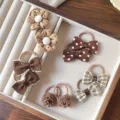 Vista dettagliata di vari elastici e fiocchi per capelli marroni carini per bambini in un vassoio. - Set di 5 Paia / Caffè