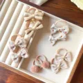 Primo piano dettagliato di elastici per capelli da bambini con fiocchi e morbidi pompon. - Set di 5 Paia / Cammello