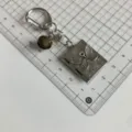 Primo piano del portachiavi con medaglione a libro di falena argento gotico con campanello vintage. - QX-B9