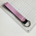Detail shot of a pink and black neoprene wrist lanyard keychain showing length and build quality. - Pink