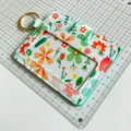 Floral print card holder detail view with clear ID window, card slots and gold keyring. - Light Blue