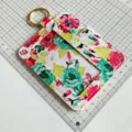 Floral print leather card holder detail with clear ID window and gold keyring for women. - Colorful