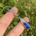 Nahaufnahme eines klaren Glas-Wunschflaschen-Schlüsselanhängers mit blauen Sternen. - Saphirblau