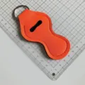 Détail de porte-baume à lèvres en néoprène orange vif avec coutures propres et anneau porte-clés. - Orange