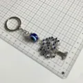 Details of evil eye key ring with tree pendant and blue rhinestones on grid background. - Rhinestone Tree of Life