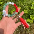 Detail shot of colorful beaded wristlet keychain featuring red PU leather tassel and bow charm. - Red Green White Mix