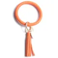 Gros plan sur le porte-clés bracelet rond en cuir orange avec pompon et anneau métallique. - Orange
