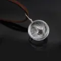 Glass globe pendant featuring real dandelion seeds inside on brown suede cord close up detail view - Double Dandelion / Brown Leather Rope