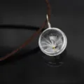 Close-up detail of a clear glass globe pendant featuring a delicate natural dandelion seed inside. - Single Dandelion Round / Brown Leather Rope