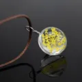 Close-up detail of the transparent glass globe pendant featuring yellow dried flowers. - Golden Gypsophila / Brown Chain