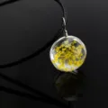 Detailed macro shot of a delicate glass ball pendant necklace filled with pretty yellow dried flowers. - Golden Gypsophila / Black Chain