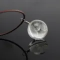 Close-up of a clear glass ball pendant necklace featuring real dandelion seeds inside. - 3 Dandelions / Brown Chain