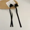 Detailed shot of black bow hair clip with rhinestone star charm, elegant hair accessory. - Black