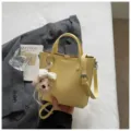 Yellow leather tote handbag with cute puppy plush charm, stylish shoulder crossbody bag. - Yellow + Pendant