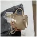 Chic beige textured leather tote bag with cute bear charm for daily commuting and leisure. - Off-White with Charm