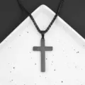 Vista dettagliata di una collana con ciondolo a croce nera su vassoio bianco, design elegante. - 40+5cm / Nero