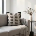Detail view of a stylish black and white textured throw pillow on a modern gray sofa. - Wide Border Fringe Plaid