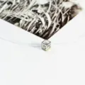 Detailed close-up of a sparkling cube crystal pendant on a transparent invisible necklace line. - Fishing Line Chain