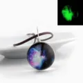 Round galaxy glass pendant necklace with brown cord and glowing night effect detail view. - Stardust 12