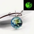 Detail view of the glowing earth glass pendant necklace with brown cord showing luminous night effect. - Earth
