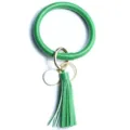 Primo piano del portachiavi rigido in pelle verde con nappa coordinata e dettagli dorati. - Verde