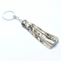 Detailed shot of a stylish snake print leather tassel keychain with a shiny silver metal ring. - Snake Print