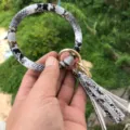 Vista dettagliata del portachiavi bracciale in pelle PU con motivo serpente e nappina. - Motivo Oro Argento