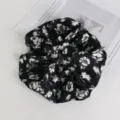 Primo piano dettagliato di un elegante elastico per capelli floreale nero e morbido. - Nero