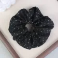 Primo piano di un elastico per capelli nero a pois bianchi con trama in tessuto liscio. - pois neri