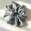 Detailopname van een glad zilveren satijnen haarelastiek, elegant design voor dagelijks gebruik. - Grijsblauw