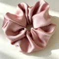 Close-up van een roze satijnen haarring met gladde textuur en glanzende stofdetail. - Roze