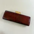 Detailansicht der dunkelroten Kroko-Textur Abendtasche mit goldenem Kettenschlossverschluss. - Burgunderrot