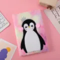Close-up detail of the cute plush penguin notebook with fluffy colorful cover and crown design. - Colorful Penguin
