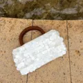 Borsa bianca in paillettes con dettaglio ravvicinato della texture e manico legno pregiato. - Bianco