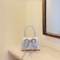 Silberne Mini-Handtasche mit funkelnder Strass-Schleife und zarten Quastenketten elegant. - Silber