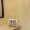 Kleine weisse Handtasche mit glitzernder Strass Schleife und feinen Quasten für Damen. - Weiß