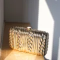 Exquisite twisted metallic clutch bag detail, high-end minimalist design for evening parties. - Champagne