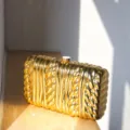 Gold metallic twisted texture hard shell clutch bag, elegant minimalist evening bag detail. - Gold